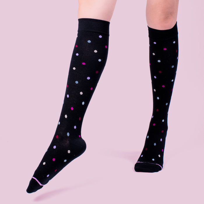 Knee-high black compression socks with colorful polka dots in pink, purple, and white.