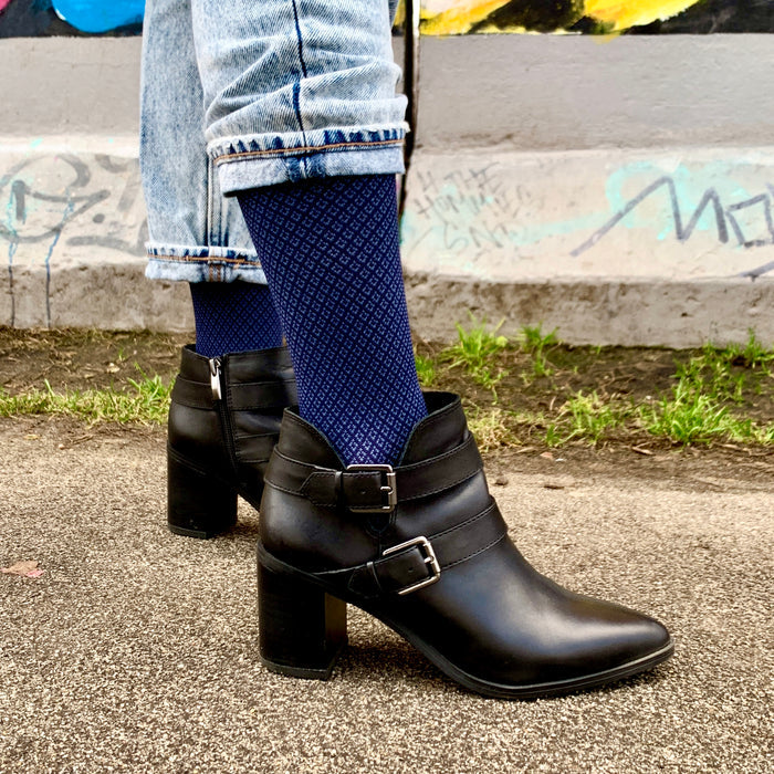 Knee-high navy compression socks are worn with black heeled ankle boots and rolled-up denim jeans.