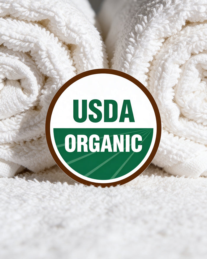 Stack of soft white towels with a USDA Organic certification seal, representing Rustic Strength's organic fabric softener